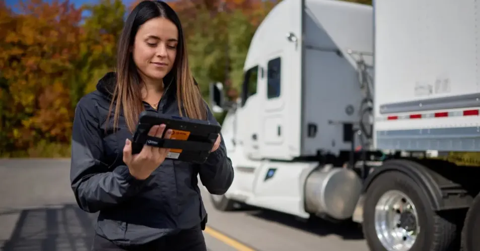 truck-driver-technology-enhancement-isaac-instruments A truck driver examines a handheld ISAAC Instruments device, ready to employ advanced fleet management technology on the road.